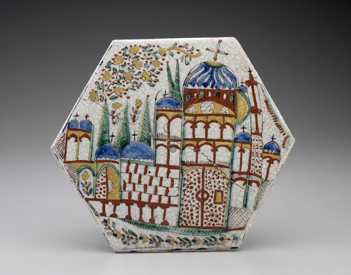 Hexagonal ceramic tile painted with a church complex of blue domes and arcades